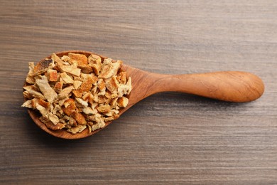 Photo of Spoon with dried orange zest seasoning on wooden table, top view