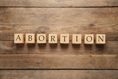 Word Abortion made of cubes on wooden background, flat lay
