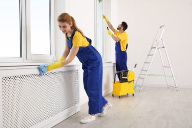 Professional janitors in uniform cleaning spacious room