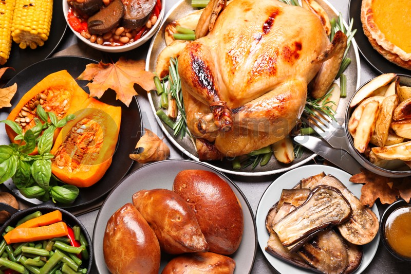 Traditional Thanksgiving day feast with delicious cooked turkey and other seasonal dishes served on grey table, flat lay