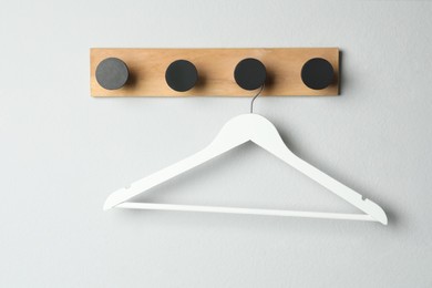 Rack with empty clothes hanger on white wall