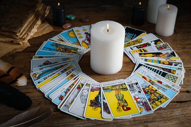 Burning candle surrounded by tarot cards on wooden table