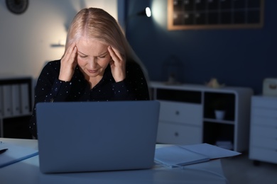 Overworked mature woman with headache in office