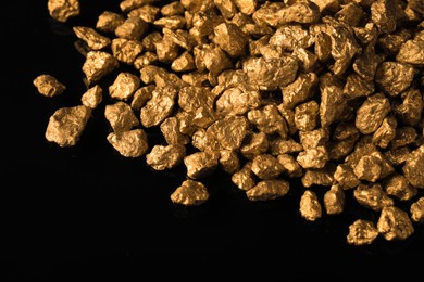 Pile of gold nuggets on black background, closeup