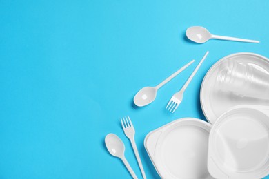 Disposable tableware on light blue background, flat lay. Space for text