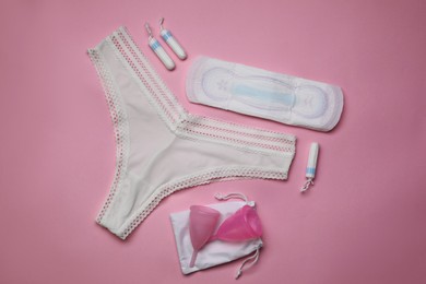 Flat lay composition with woman's panties and menstrual hygiene products on pink background