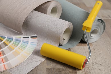 Wall paper rolls, color palette and tool on wooden floor