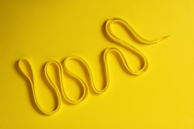 Shoe lace on yellow background, top view