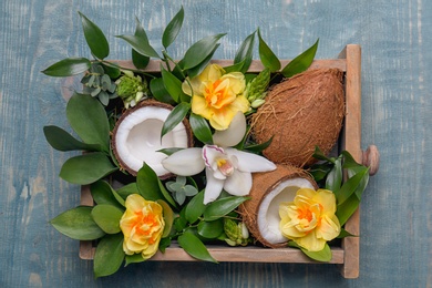 Box with coconuts and flowers on wooden background