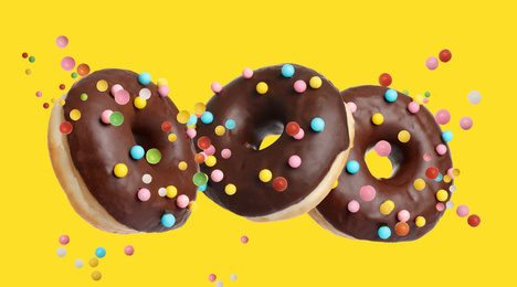 Set of falling delicious donuts on yellow background