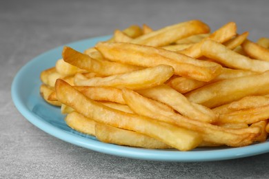 Turquoise plate with delicious french fries on light gray marble table, closeup
