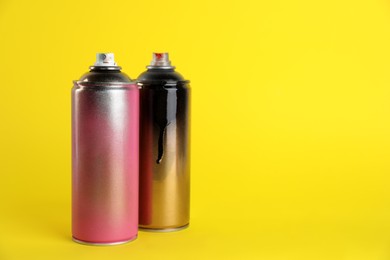 Used cans of spray paints on yellow background. Space for text