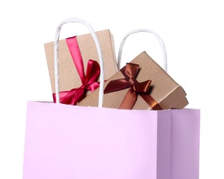 Photo of Pink paper shopping bag full of gift boxes on white background
