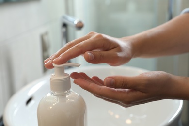 Woman applying liquid soap on hand in bathroom, closeup