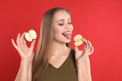 Photo of Young woman with cut apple on red background. Vitamin rich food