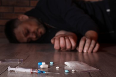 Overdosed man indoors, focus on different drugs