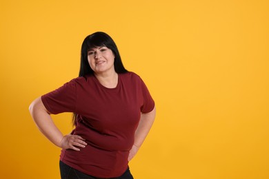 Beautiful overweight mature woman with charming smile on yellow background. Space for text