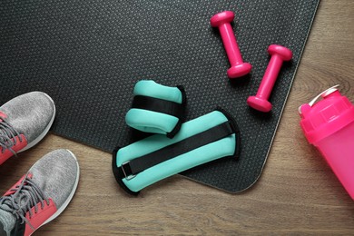Turquoise weighting agents and sport equipment on wooden table, flat lay