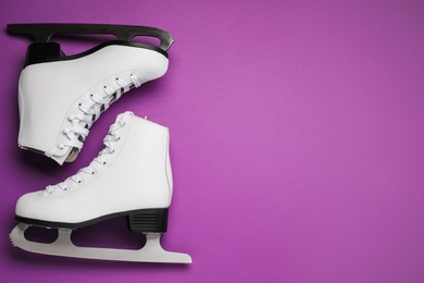 Pair of figure ice skates on purple background, flat lay. Space for text