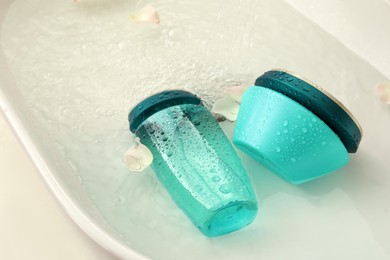 Hair care cosmetic products with flower petals and water in sink