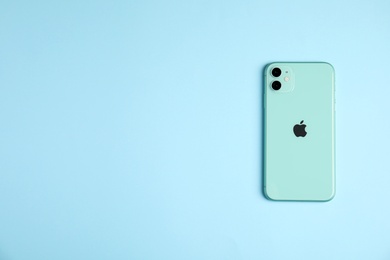MYKOLAIV, UKRAINE - JULY 10, 2020: New modern Iphone 11 Green on light blue background, top view. Space for text