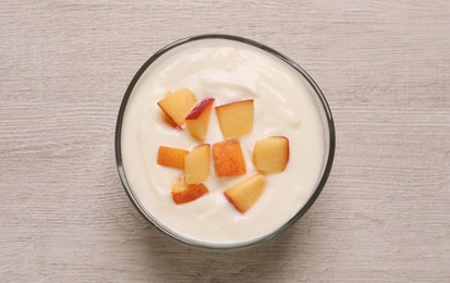 Delicious yogurt with fresh peach on light wooden table, top view