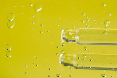 Photo of Pipette near serum drops on beautiful mirror, closeup with space for text. Toned in yellow