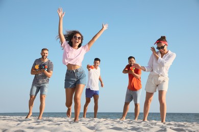 Photo of Group of friends with water guns having fun on beach