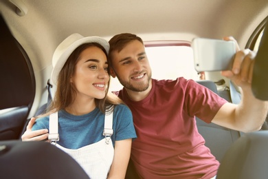 Happy young couple taking selfie in car