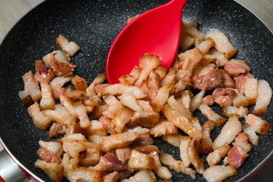 Photo of Cooking cracklings in frying pan, closeup. Pork lard