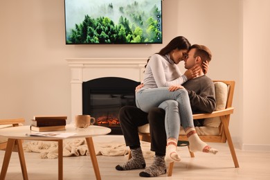 Photo of Happy lovely couple spending time together near fireplace at home