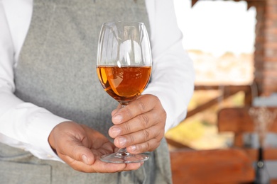 Waiter holding glass of wine in outdoor cafe, closeup