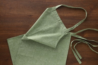 Photo of Clean kitchen apron with pattern on wooden table, top view