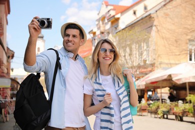 Photo of Happy couple of tourists with camera on city street