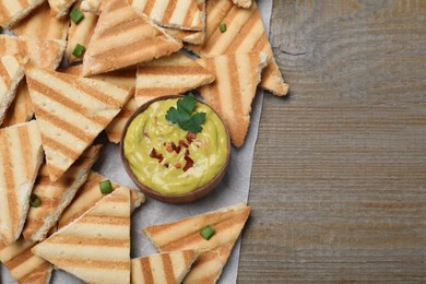 Delicious pita chips and hummus on wooden table, top view. Space for text