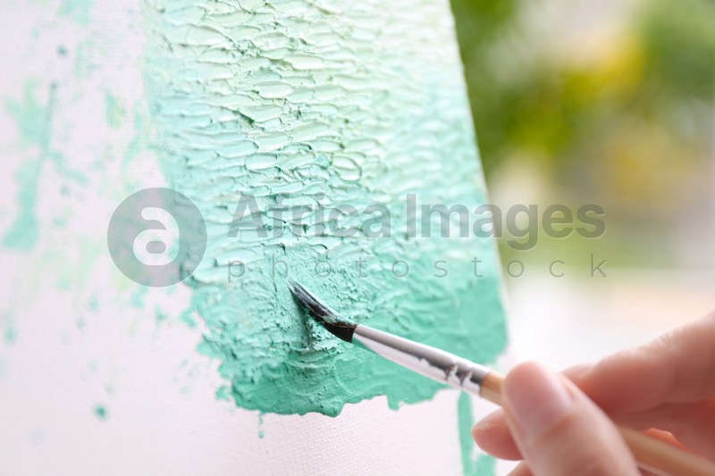 Artist painting on canvas with brush, closeup
