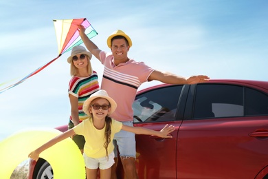 Happy family with inflatable ring and kite near car outdoors. Trip to beach