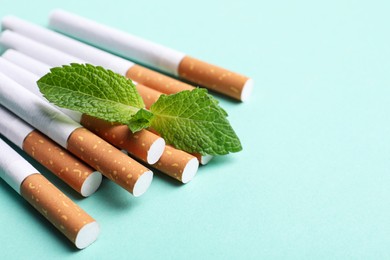 Menthol cigarettes and mint on turquoise background, closeup. Space for text