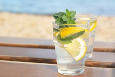 Refreshing water with lemon and mint on wooden table outdoors. Space for text