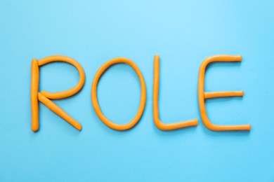 Word Role made with orange plasticine on light blue background, flat lay