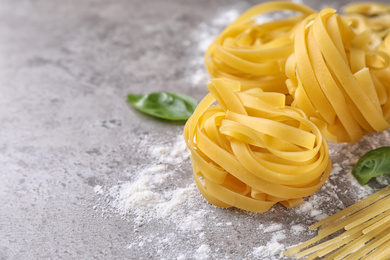 Uncooked tagliatelle pasta on grey table, closeup. Space for text