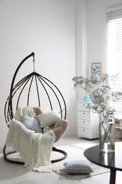 Photo of Cozy hanging chair with fairy lights in modern living room. Interior design