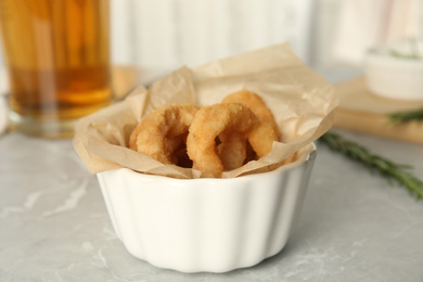 Delicious crunchy fried onion rings on grey marble table