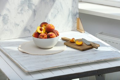 Bowl of juicy peaches and double-sided backdrop on table in photo studio