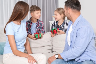 Photo of Little children presenting their parents with gifts at home
