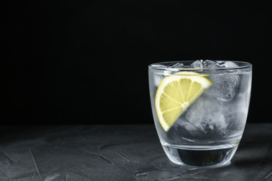 Water with ice cubes and lemon on grey table, closeup. Space for text