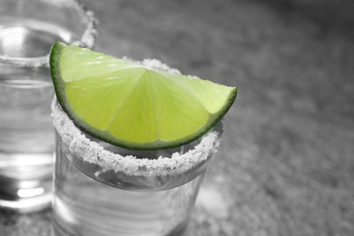 Mexican Tequila shot with salt and lime slice on grey table, closeup