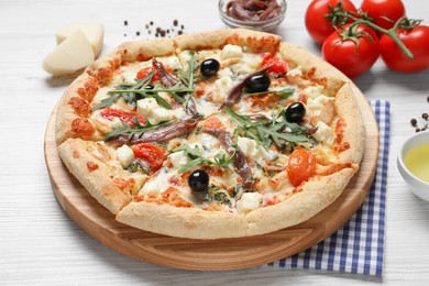 Photo of Tasty pizza with anchovies and ingredients on white wooden table
