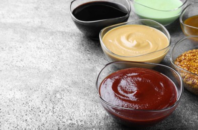 Many different sauces on grey table, space for text