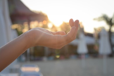 Girl holding her hand against sunlight on beach, closeup